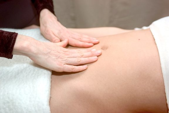 Touchlife Massage - Bauch Hände legen sich sanft auf den Bauch einer liegenden Person.