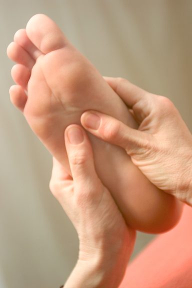 Touchlife Massage - Füße Eine Hand massiert die Fußsohle einer Person.