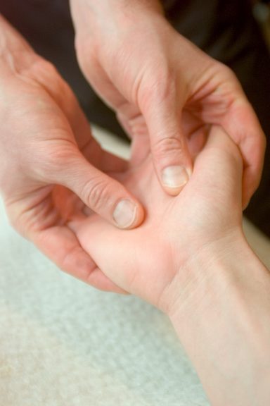 Touchlife Massage - Hände Zwei Hände halten das Handgelenk einer anderen Hand zur Untersuchung oder Massage.